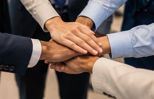 Team members stacking hands to represent collaboration